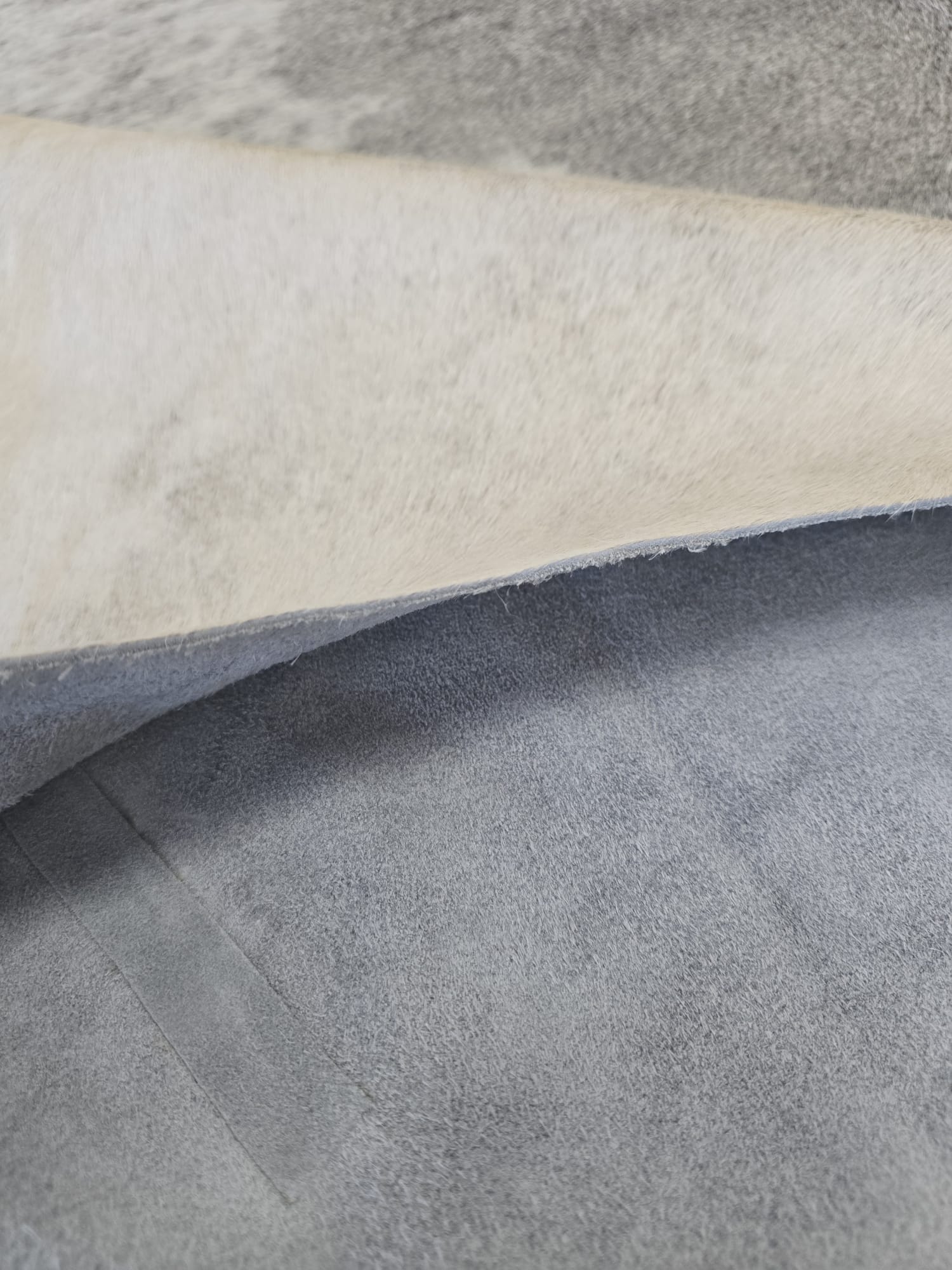 Goveđa koža Albina 226x238 od prirodne goveđe kože u ivory bijeloj, srebrno sivoj i grafitno sivoj nijansi s prirodnim organskim oblikom i kratkom dlakom.