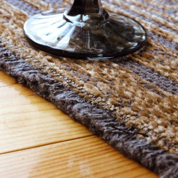 Tepih Nero tamne podloge s bakrenim detaljima, klasičnim okvirom i mekanom šenil površinom od recikliranog pamuka i poliestera.