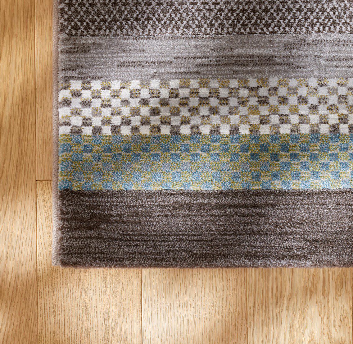 Tepih GENT MODRINA moderni prugasti tepih u plavim, zelenkastim, bež, sivim i ivory tonovima, izrađen od 100% PP Heatset materijala s teksturiranom površinom.