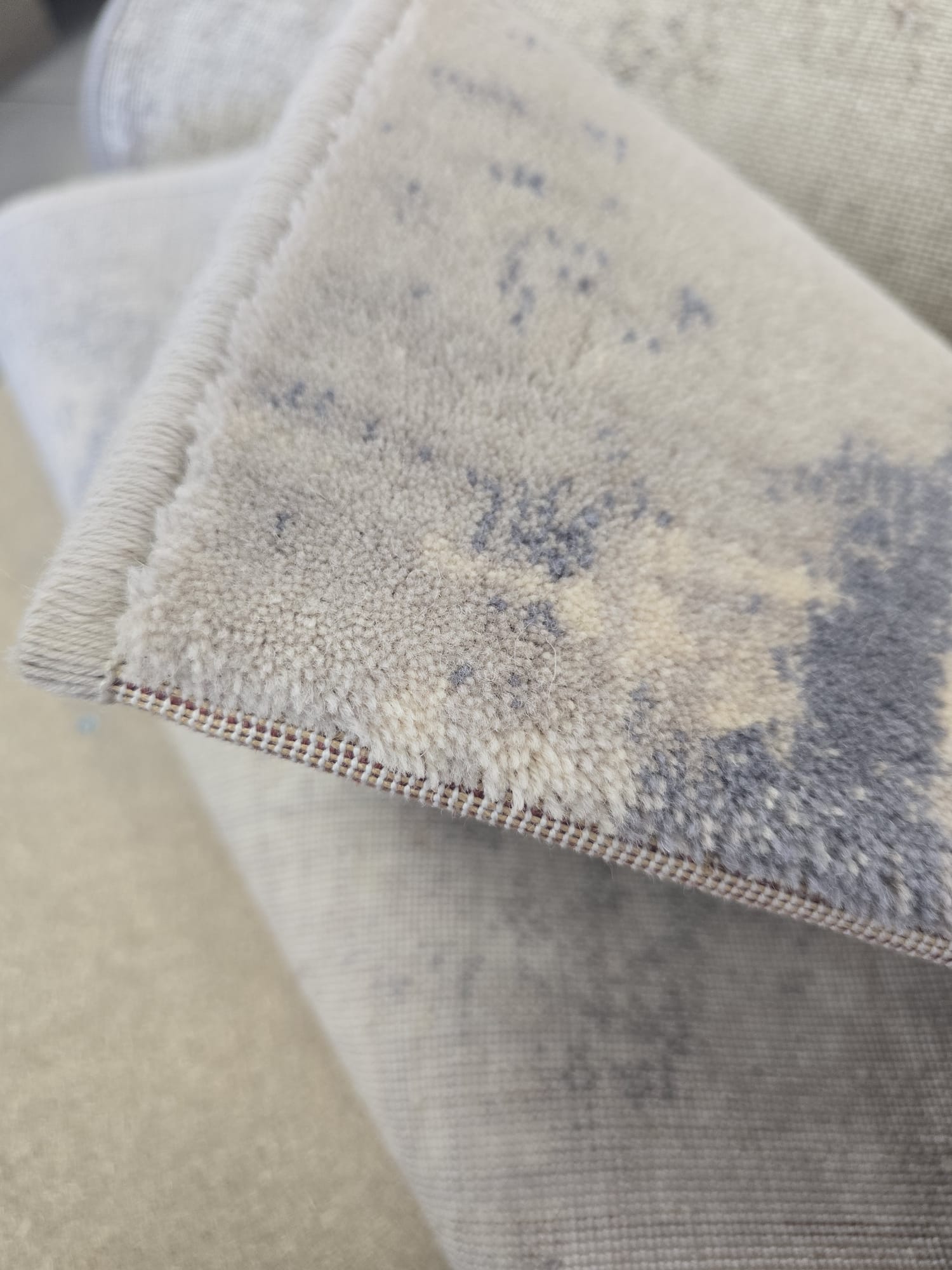 Vuneni Tepih Blu moderni vintage tepih u plavim, ivory, bež i sivim tonovima, izrađen od 100% prirodne vune, s mekanom baršunastom površinom.