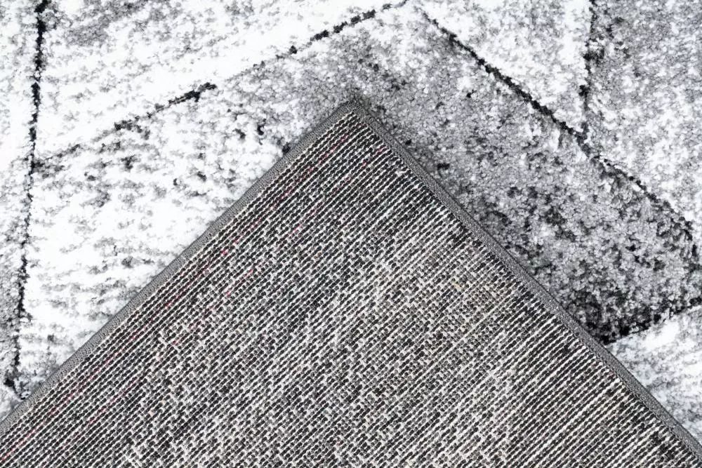 Tepih HEXA moderan je geometrijski tepih u sivim, antracitnim i svijetlim neutralnim tonovima. Izrađen je od 100% PP Heatset Frisee, što mu daje puniju, mekanu i praktičnu površinu za svakodnevno korištenje. Posebno se ističe ručno rezbarenim 3D efektom, koji naglašava geometrijske linije i površini daje dodatnu dubinu. Ukupna visina iznosi približno 14 mm, a masa oko 2.200 g/m². Jutena podloga dodatno doprinosi stabilnosti konstrukcije. Tepih HEXA odličan je izbor za dnevni boravak, spavaću sobu ili moderan apartman.