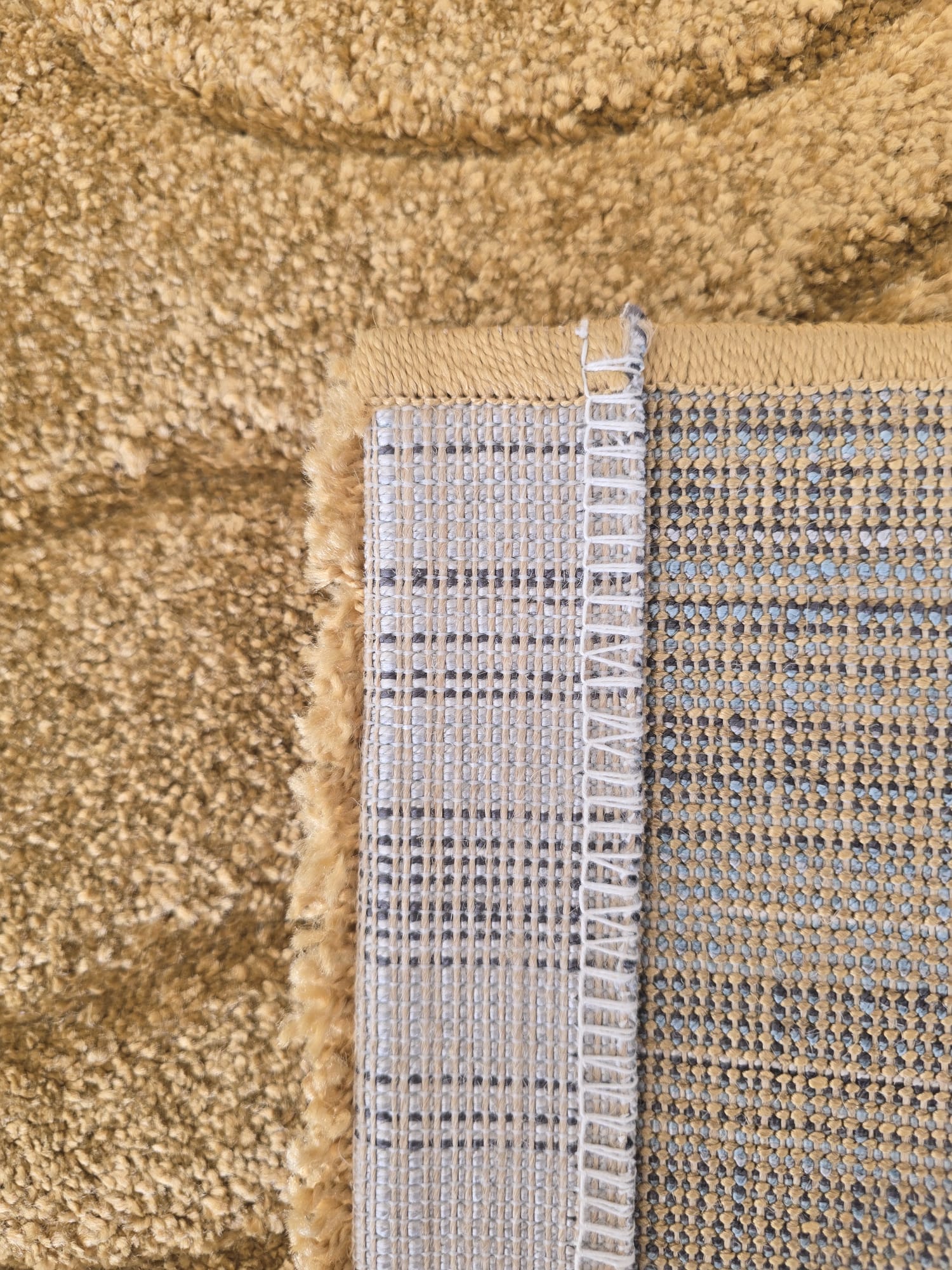 Tepih HOME OCHRE oker-zlatni tepih od 100% polipropilena, s ručno rezbarenim valovitim reljefom, florom 12 mm i mekanom površinom.