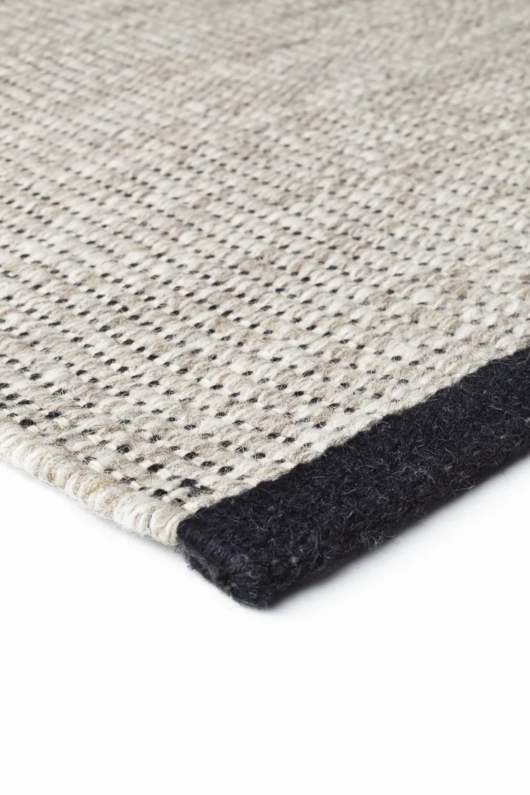 Vuneni Tepih Ligne Pure MARVEL BLACK ručno je tkan od 95% novozelandske vune i 5% pamuka, uz ukupnu masu od približno 2.000 g/m². Ravno tkana prirodna podloga ukrašena je diskretnim crnim nitima i naglašenim rubovima koji tepihu daju jasan, suvremen i profinjen karakter. Dimenzije koje trenutačno nisu dostupne moguće je naručiti. Očekivani rok dolaska u našu poslovnicu u Splitu iznosi 10 do 15 radnih dana.